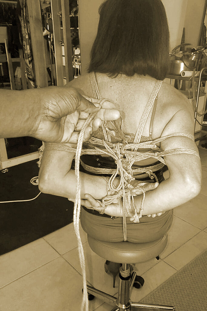 La main experte de Maîtresse Akina réalisant un shibari